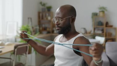 Tekerlekli sandalyedeki Afrikalı Amerikalı adamı evde egzersiz yaparken çek.