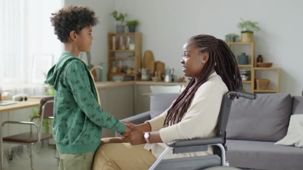 Средний Снимок Маленького Сына Обнимающего Радостную Афроамериканскую Мать Инвалидном Кресле — стоковое видео