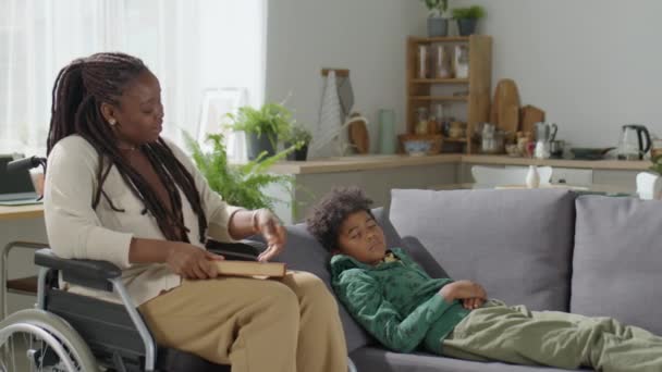 Afectuosa Mãe Afro Americana Livro Fechamento Cadeira Rodas Acariciando Filhinho — Vídeo de Stock