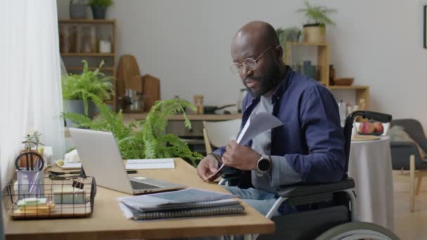 Afroamerikansk Man Rullstol Diskuterar Företagspapper Online Videosamtal Bärbar Dator Medan — Stockvideo