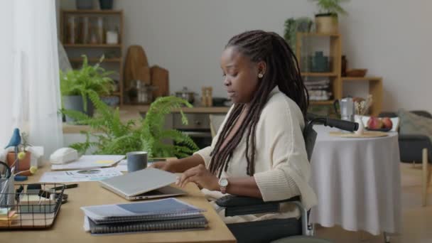 Ung Afroamerikansk Kvinna Rullstol Rider Till Skrivbordet Öppna Laptop Och — Stockvideo