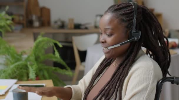 Strzał Dół Afroamerykanki Wózku Inwalidzkim Pomocą Bezprzewodowego Zestawu Słuchawkowego Podczas — Wideo stockowe
