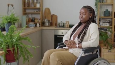 Özürlü genç Afrikalı Amerikalı kadın portresi tekerlekli sandalyede oturuyor ve kameraya poz veriyor.