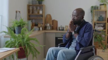 Engelli Afrikalı Amerikalı bir adam tekerlekli sandalyede oturuyor ve bütün gün avuç içleriyle dua ediyor.