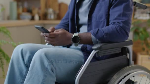 残疾黑人坐在轮椅上 在家里用智能手机发短信的剪影 — 图库视频影像