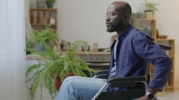 Tekerlekli Sandalyedeki Afrikalı Amerikalı Adamın Gözlüğünü Çıkarırken Gözlerini Ovuştururken Pencereden — Stok video