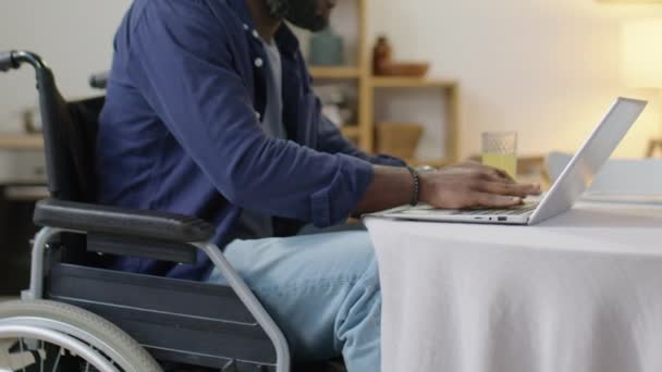 坐在轮椅上喝果汁 在家里笔记本电脑上打字的黑人截图 — 图库视频影像