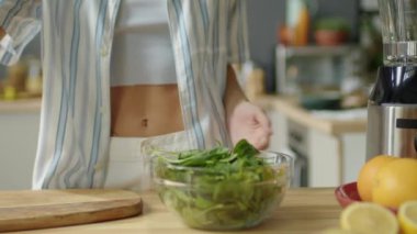 Kadın blogcunun mutfak masasında durup taze ıspanak, brokoli, yabanmersini ve zerdeçal tozunu kameraya çekerken sağlıklı besinlerin video tarifini çekerken görüntülerini kestim.