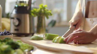 Mutfak masasında taze yeşil elma keserken evde sağlıklı bir yemek hazırlayan kadının ellerini yakın plan çekin.