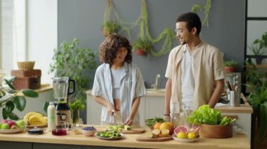 Mutfak masasında meyve kokteyli hazırlarken genç çiftin sohbet ederken evde geçirdiği orta boy bir fotoğraf.