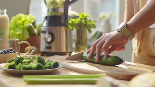 自宅で健康的なベジタリアン料理を準備しながら キッチンテーブルで新鮮なキュウリを切断する男の手の近くのショット — ストック動画