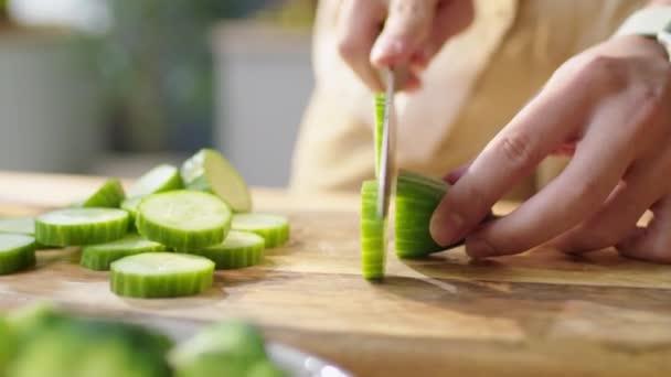 男子在厨房桌子边的木板上切碎新鲜黄瓜 同时在家中准备健康晚餐的特写镜头 — 图库视频影像
