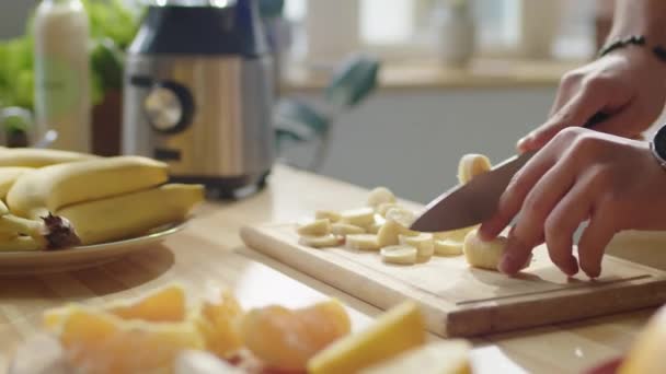 Nahaufnahme Von Menschenhänden Die Küchentisch Bananen Auf Einem Holzbrett Schneiden — Stockvideo