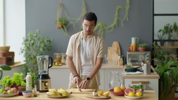 Medium Long Shot Male Blogger Cutting Banana Kitchen Table Speaking — Stock Video