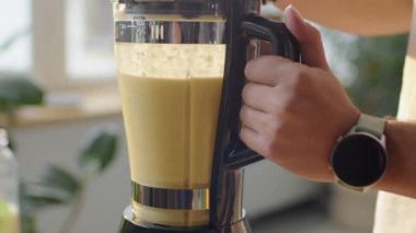 Mutfakta meyve püresi hazırlarken elinde blender tutan tanınmayan bir adamın yakın çekim görüntüsü.