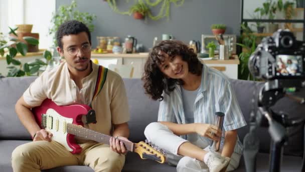 Gen Couple Sitting Sofa Talking Playing Guitar Shaker While Filming — Stock Video