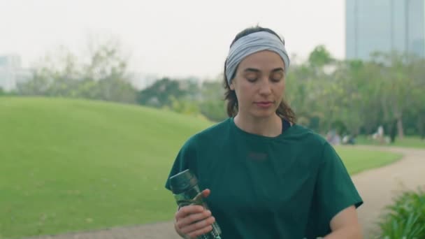 공원에서 물병과 아침에 운동을하는 스마트 워치에 시간을 운동복에 여자의 슬로우 — 비디오