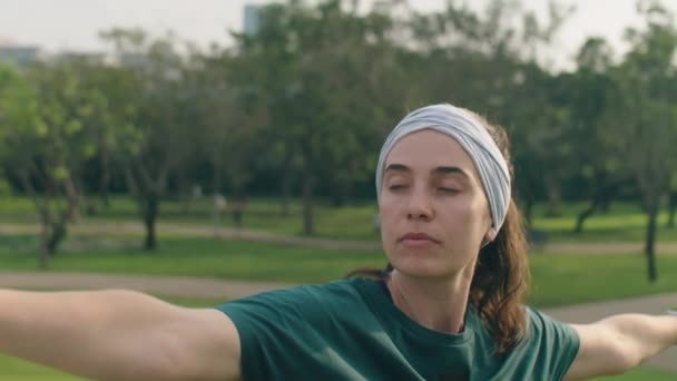 在公园里做瑜伽时 身着运动服和头带练习的女子伸出双臂摆出中等特写镜头 — 图库视频影像