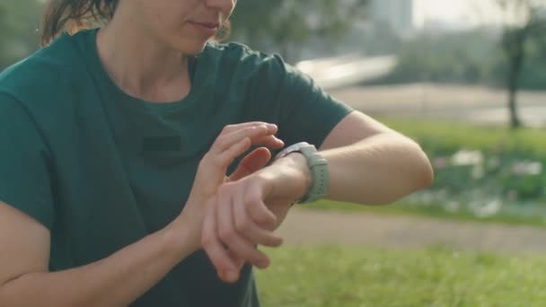 穿着运动服的女人坐在公园外面 在运动前把健身应用程序放在智能吸盘上的剪影 — 图库视频影像