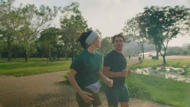 在公园里参加运动服慢跑和晨跑聊天的活动夫妻中慢镜头 — 图库视频影像