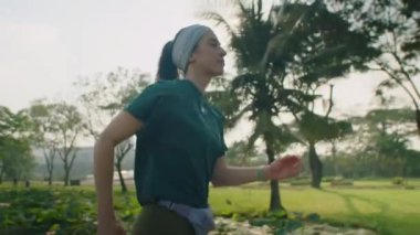 Spor giyimli genç bir kadının sabah dışarıda spor yaparken parkta koşarken orta boy fotoğrafı.