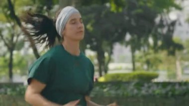 Spor giyim giymiş genç zayıf bir kadının sabah koşusu antrenmanı sırasında şehir caddesinde koşarkenki görüntüsü.