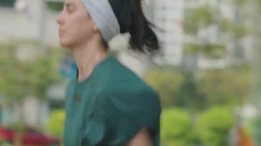 Spor giyim sektöründe genç bir kadın sabah antrenman yaparken şehir caddesinde koşuyor.