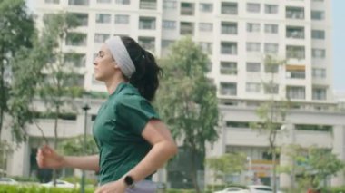 Yan görüntü, genç bayan koşucunun sabah dışarıda egzersiz yaparken caddede koşarkenki yavaş çekim görüntüsü.