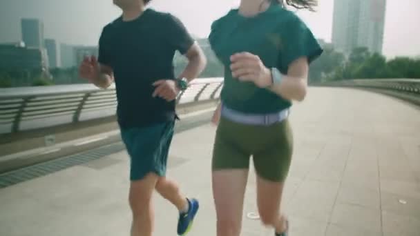 早上在城市的人行横道的桥上 一对欢快的情侣在一起跑步 他们在一起锻炼 — 图库视频影像