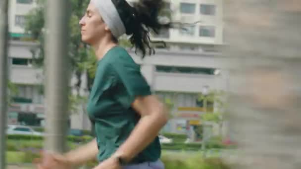 晨跑运动时沿着城市街道慢跑的年轻女运动员侧视图跟踪拍摄 — 图库视频影像