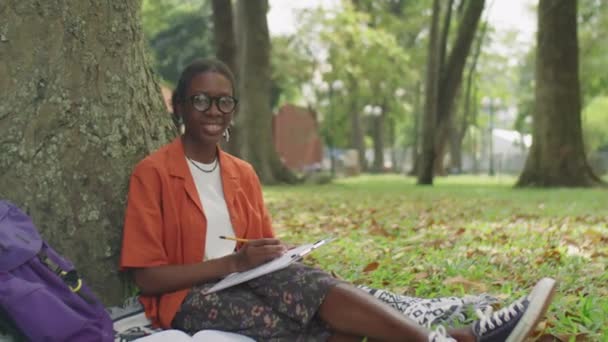 Retrato Estudante Afro Americana Alegre Sentado Árvore Parque Segurando Lápis — Vídeo de Stock