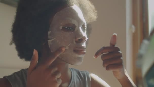年轻的非洲裔美国女人在家里的台面镜前贴上口罩的胸部照 — 图库视频影像