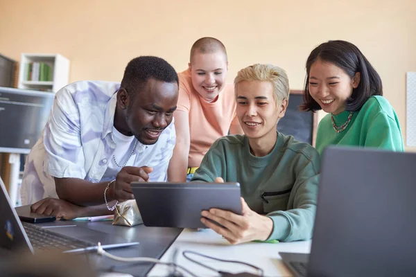 在介绍新软件的过程中 一群快乐的跨文化学生讨论了亚洲年轻人在平板电脑屏幕上的数据 — 图库照片