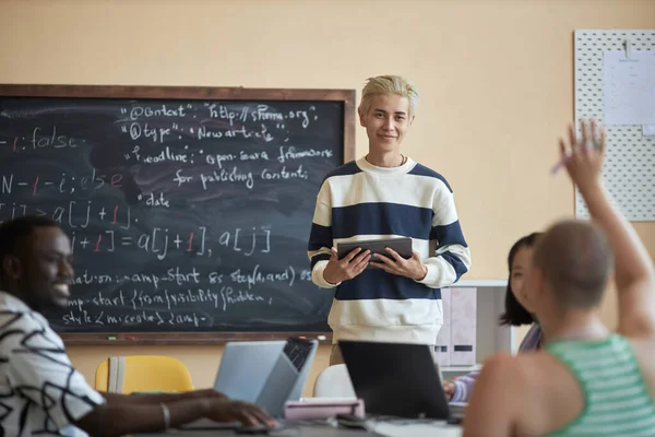快乐的年轻人 带着平板电脑 看着女学生举手提问 在计算机科学课上演讲 — 图库照片