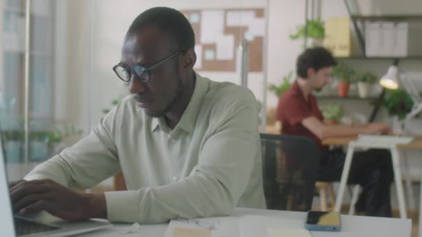 使用触摸板和笔记本电脑在办公桌上打字的非洲裔美国人办公室工作人员中的一张照片 — 图库视频影像