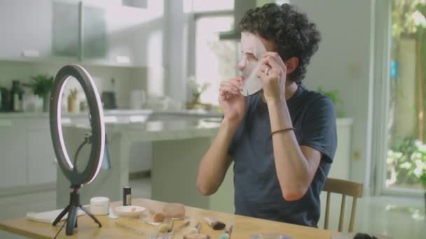 男性美容师在为社交媒体频道拍摄视频导引的过程中 在圆形灯前用智能手机对着脸和说话的中景照片 — 图库视频影像