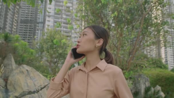 Średnie Ujęcie Młodej Azjatki Rozmawiającej Przez Telefon Podczas Spaceru Mieście — Wideo stockowe
