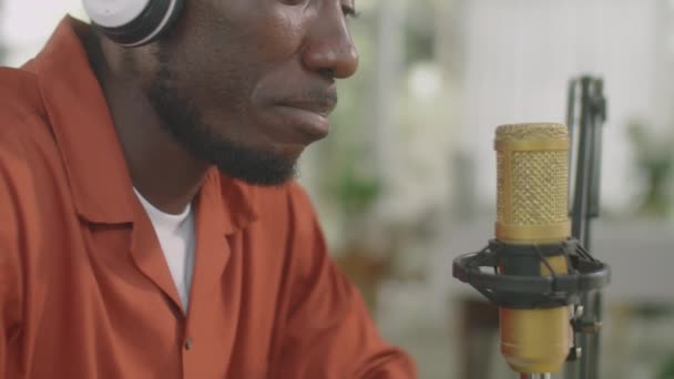 非洲裔美国人在无线耳机中一边用麦克风说话一边录制播客的截图 — 图库视频影像