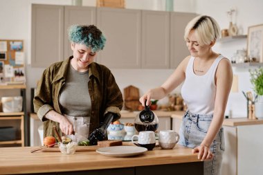 Kızlar mutfakta birlikte kahvaltı hazırlıyorlar, sandviç pişiriyorlar ve sıcak kahve koyuyorlar.