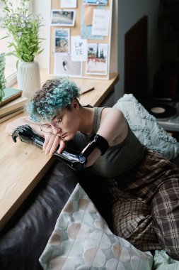 Özürlü üzgün bir kızın evde yalnız zaman geçirmesinin dikey görüntüsü.