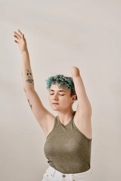 Vertical image of young woman with amputee arm standing against white background