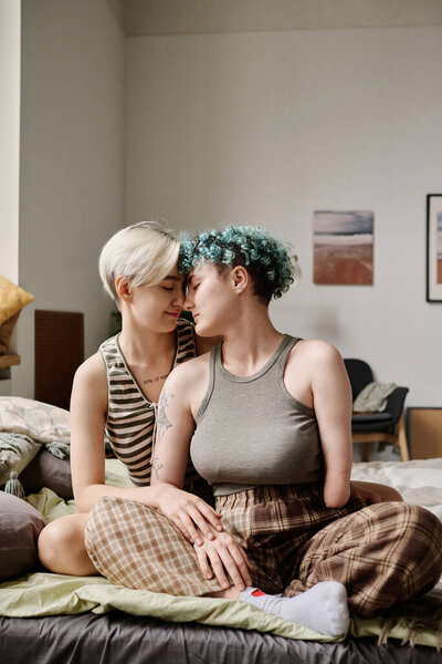 Vertical image of lovely lesbians enjoying time together in the room at home