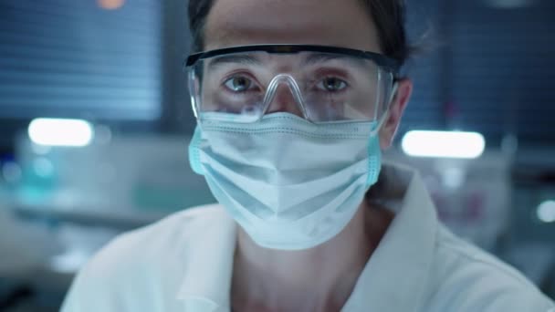 实验室中戴防护眼镜和面罩的年轻女科学家的画像 — 图库视频影像