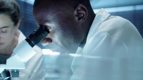 Close Skud Afrikansk Amerikansk Videnskabsmand Ser Gennem Mikroskop Taler Med – Stock-video