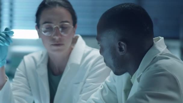 黒人男性科学者が研究室で協力しながらコーカサス女性同僚との仕事を議論 — ストック動画
