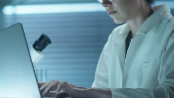 Laboratuvar Önlüklü Gözlüklü Kadın Bilim Adamının Laboratuvar Masasındaki Laptopta Çalışırken — Stok video