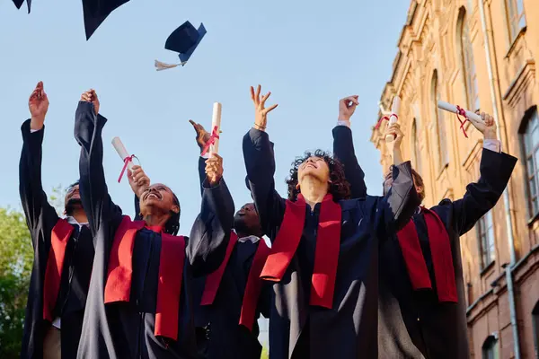 一群身穿长袍的学生站在大学近旁脱帽致敬 — 图库照片