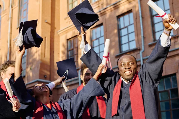 一群兴奋的多民族学生穿着毕业礼服获得毕业文凭 — 图库照片