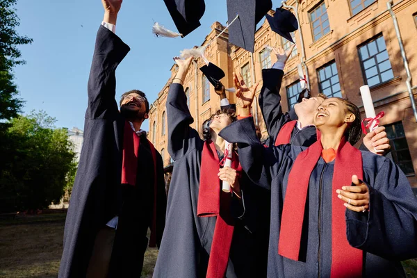 Estudantes Graduados Felizes Jogando Seus Chapéus Para Cima Enquanto Estão — Fotografia de Stock