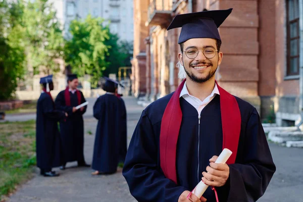 穿着长袍的学生站在室外对抗大学时对着相机微笑的画像 — 图库照片